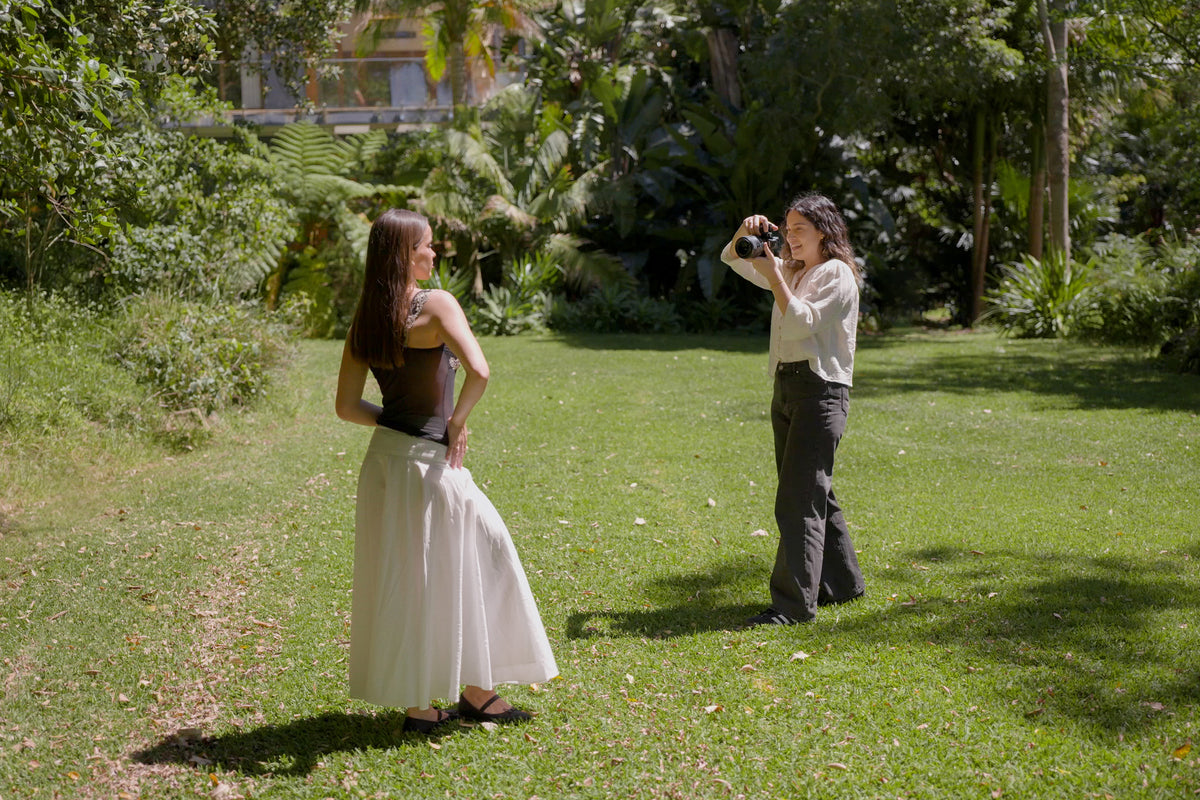 Julia Trotti photographing a model in a white skirt on a sunny lawn during a natural light portrait workshop shoot