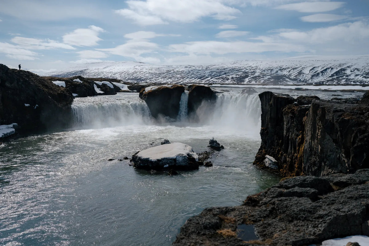 Goðafoss waterfall with snow-capped hills behind in North Iceland