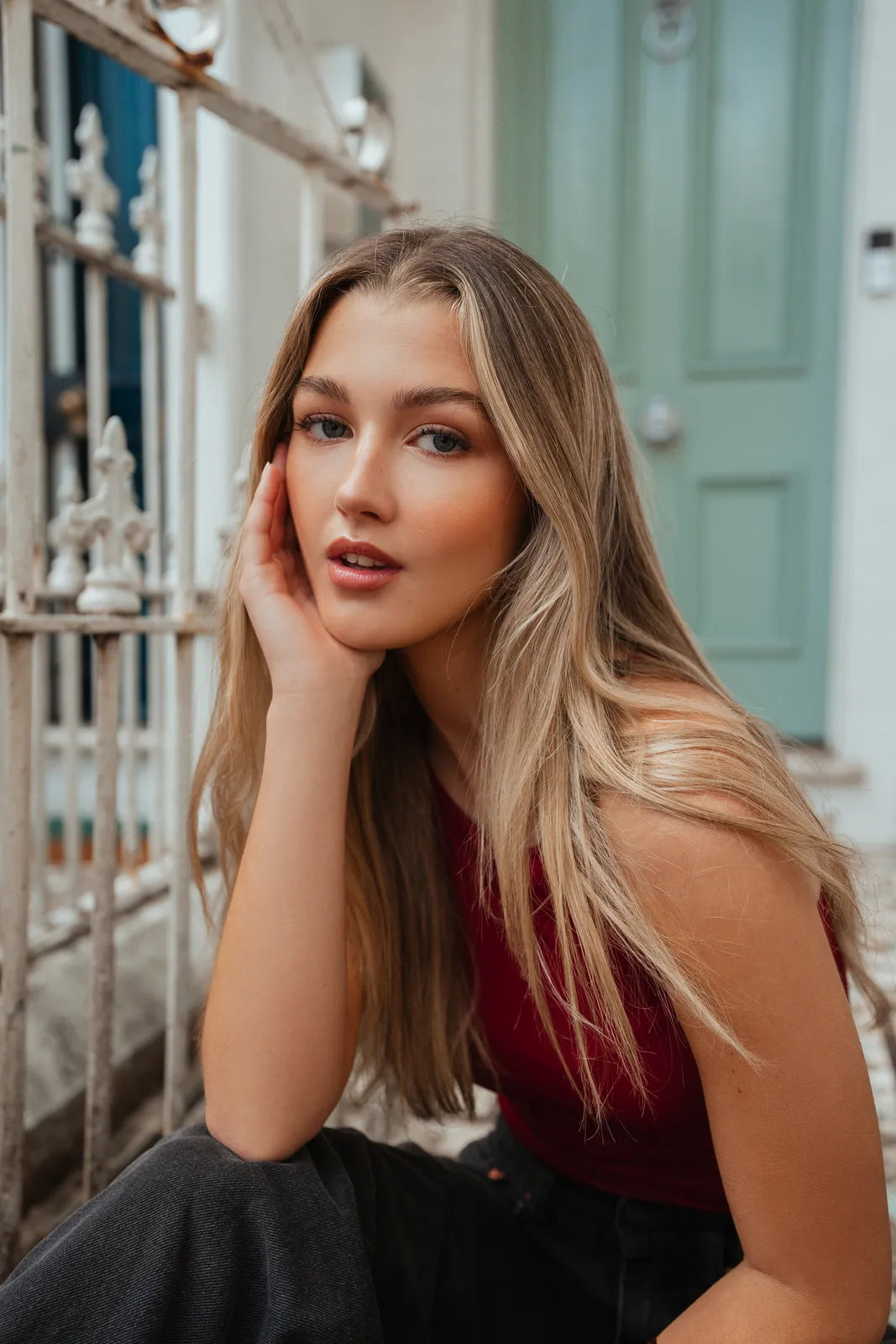 Portrait of a woman in a red top resting her face on her hand, shot on the Sony 16-35mm f2.8 GM II