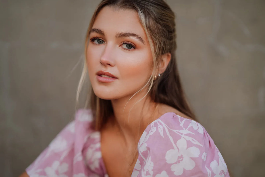 Close-up portrait of a woman with long blonde hair against a grey wall, shot on the Sony A7CR